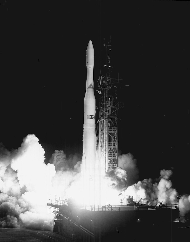 Archival black and white photo of a Delta rocket launch from 1969 with a UK flag superimposed.