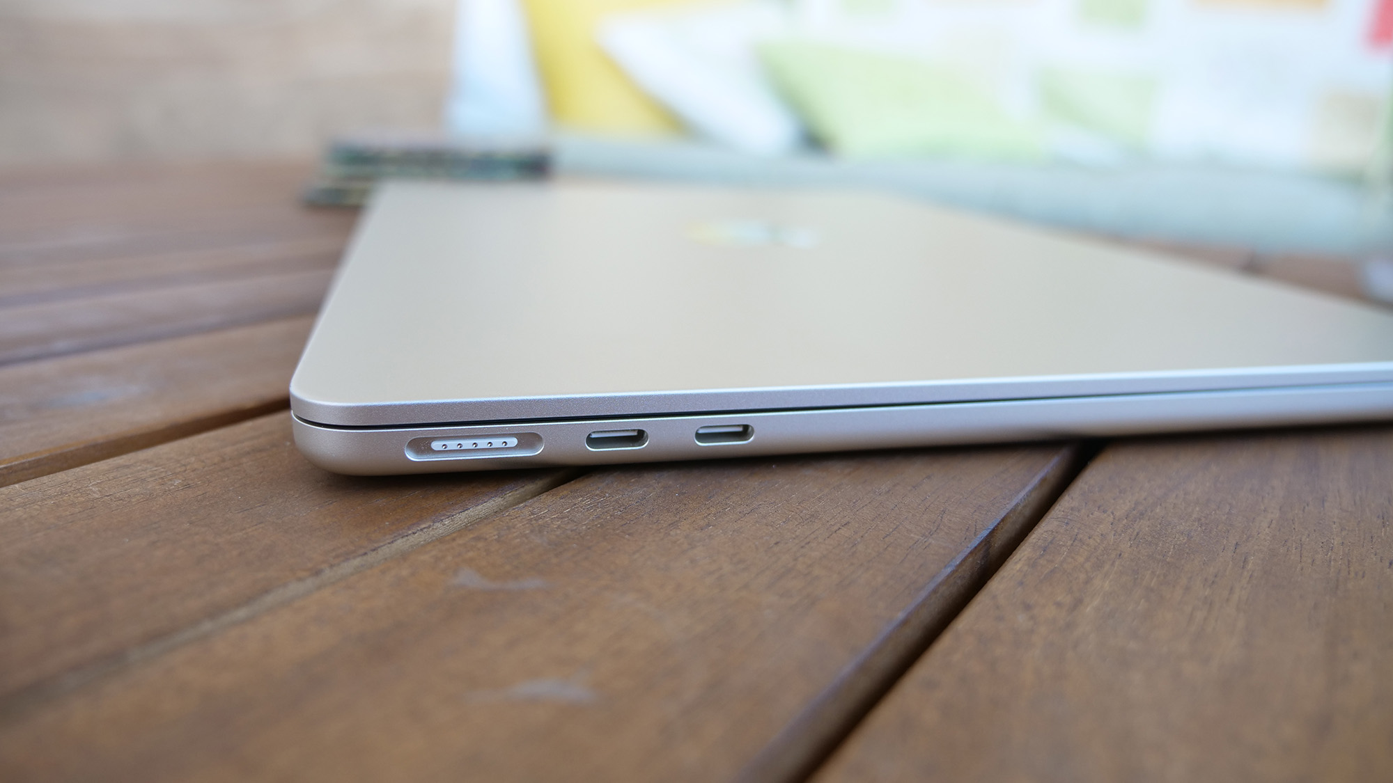 Profile view of a MacBook Air 13 M3 showing its slim chassis on a wooden surface.