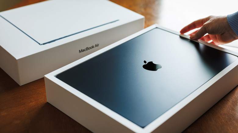 A person unboxing a new MacBook Air laptop.