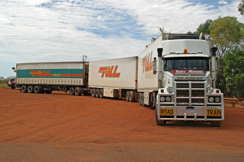 A long road train truck moving along a highway at night