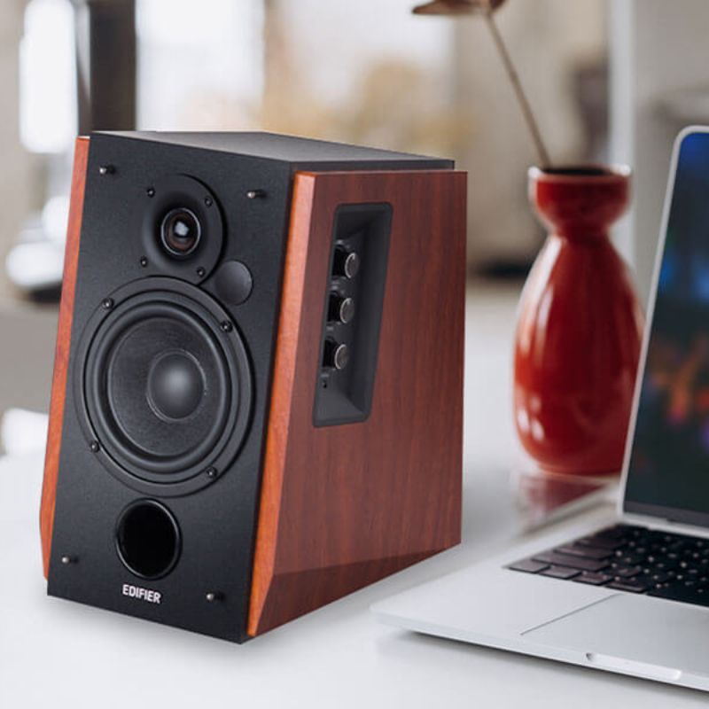 Edifier R1700BT speakers with a maple finish placed next to a laptop.