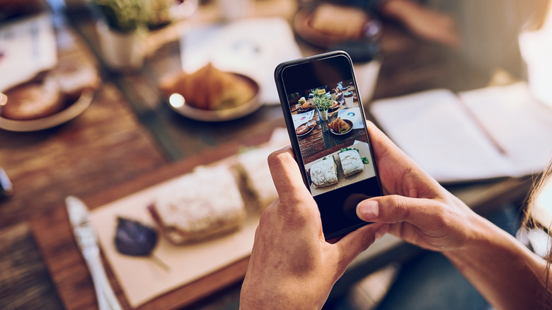 A person using a smartphone to photograph a meal at a restaurant.