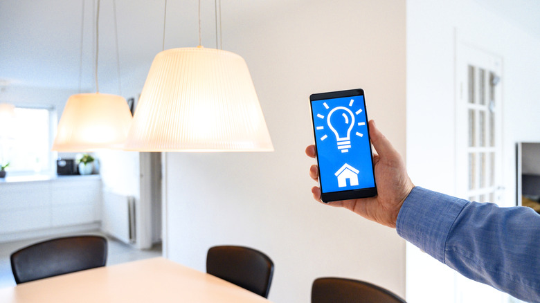Person using a mobile app to control multiple smart home light fixtures.