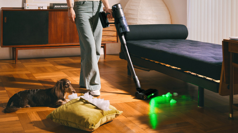 A woman using the lightweight Roborock H60 Ultra to clean a bright modern living room.