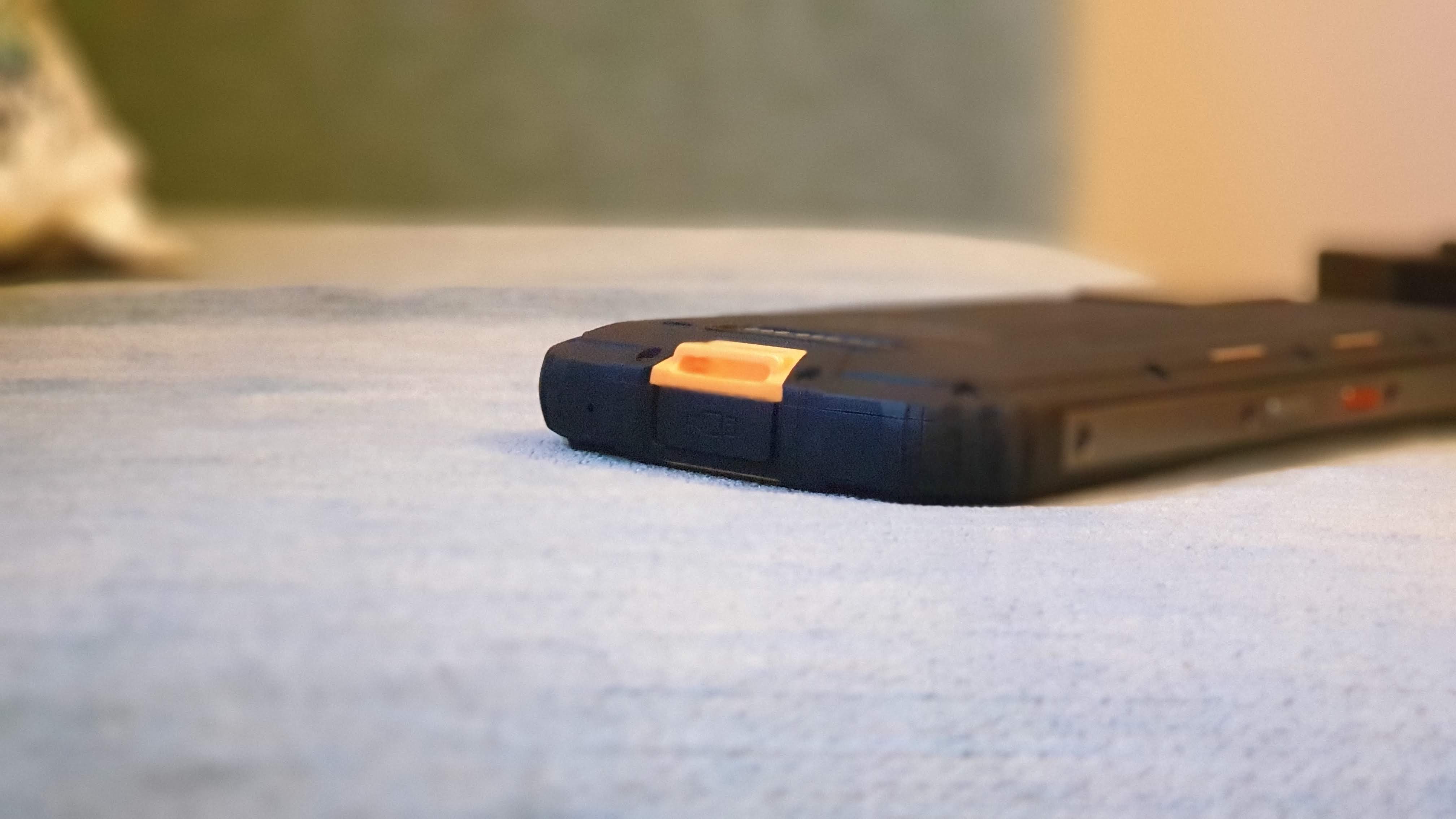 Close-up of a rubber waterproof flap covering a USB-C port on a rugged smartphone.