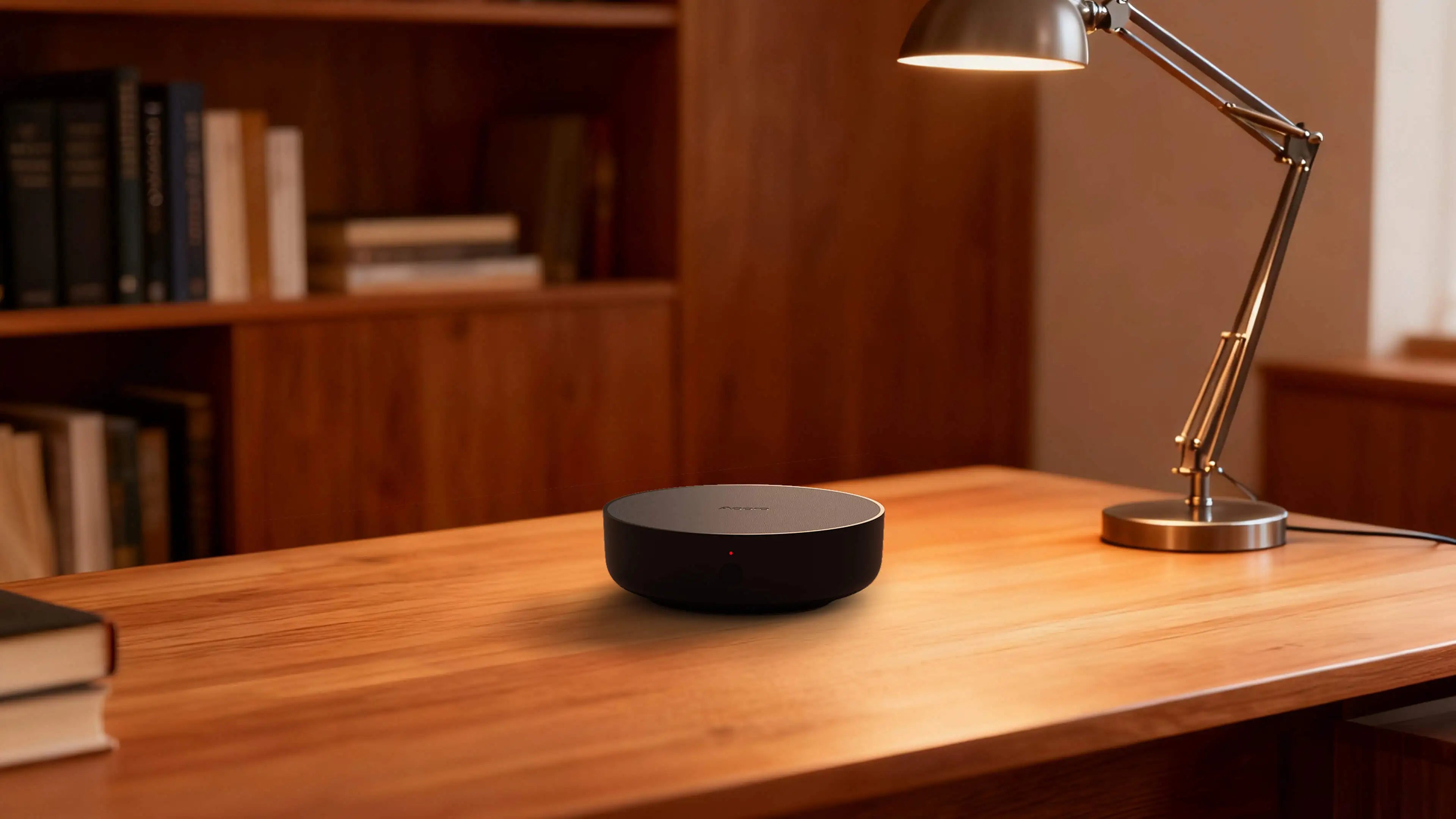The sleek, black Aqara Hub M200 placed on a wooden desk next to a minimalist lamp.