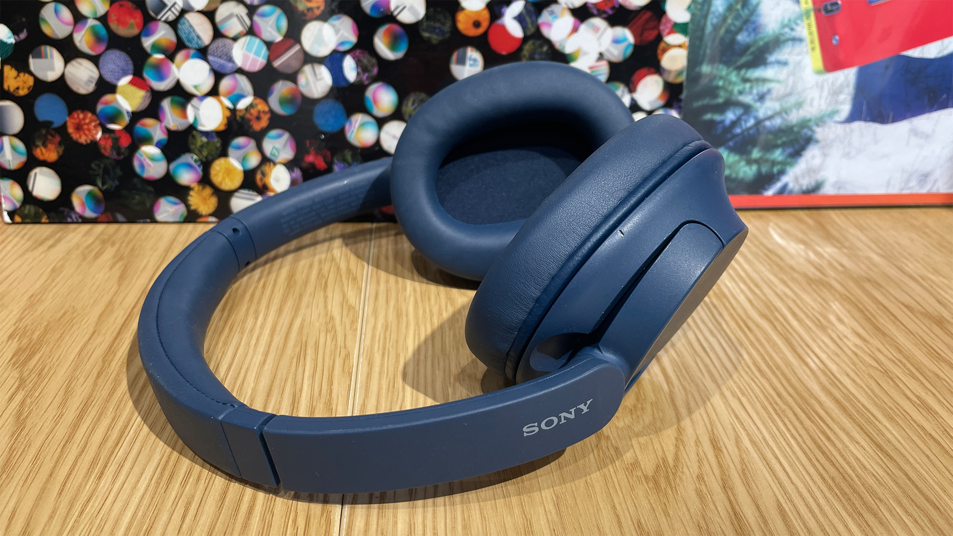 Sony WH-CH720N headphones resting on a natural wooden surface.