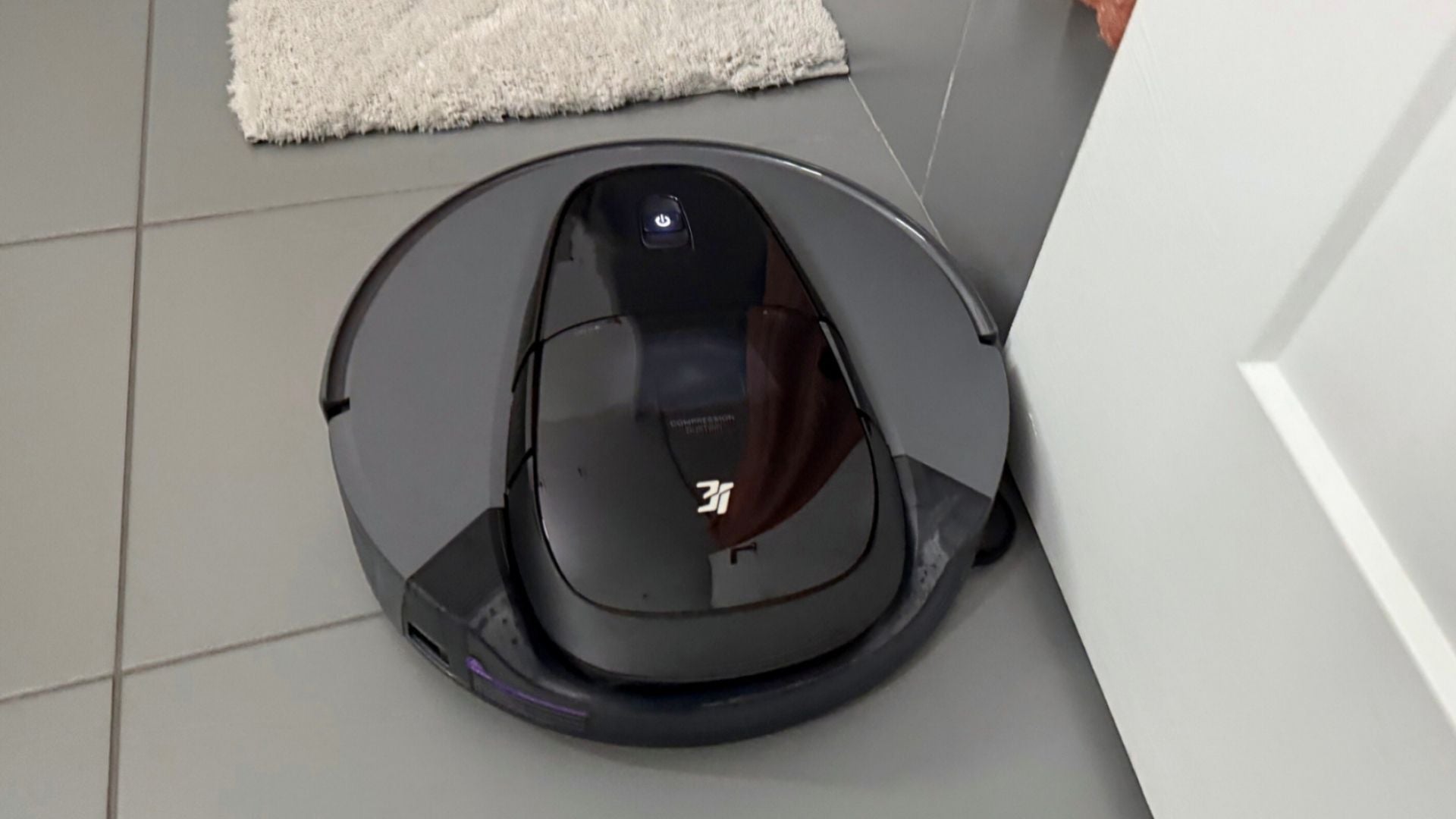 Close-up of a robot vacuum's brushes cleaning the narrow seam of a door track.