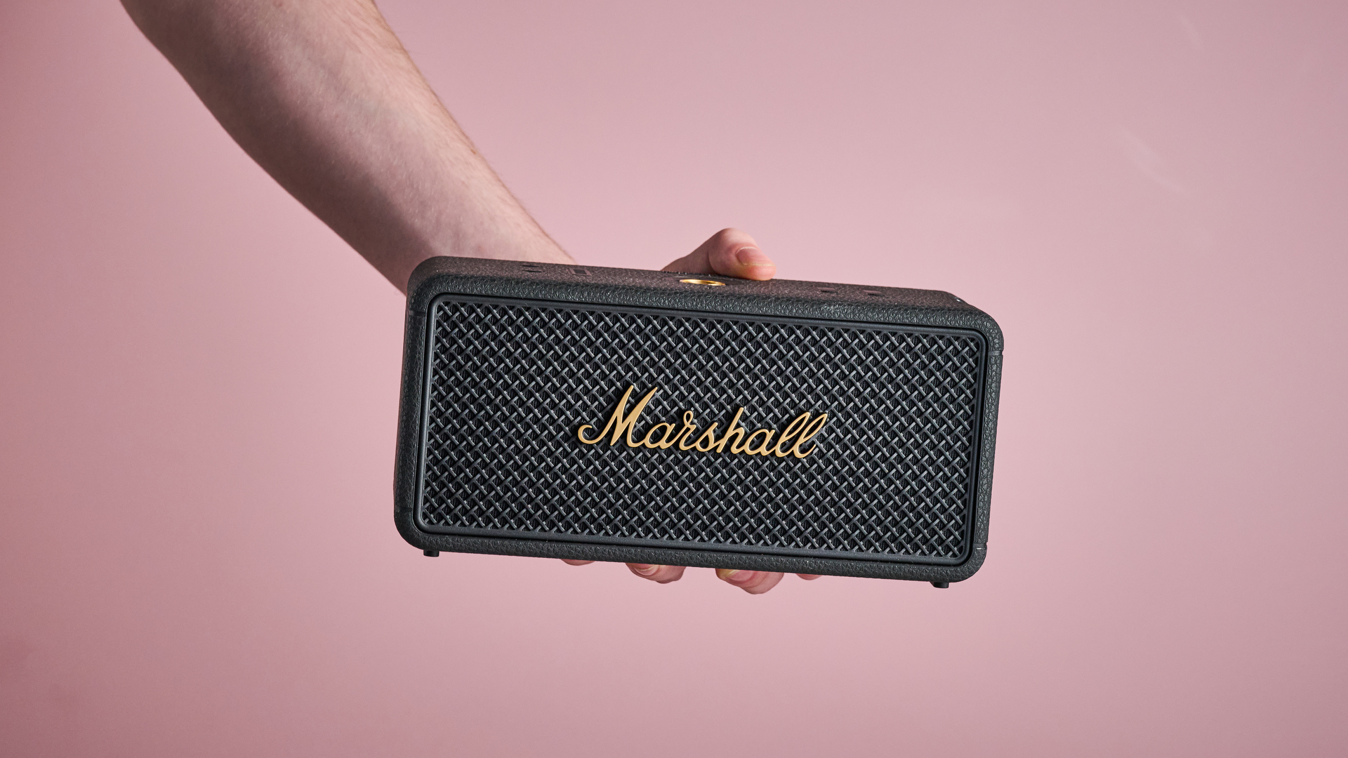 The Marshall Middleton 2 speaker being held by a person to show its size.