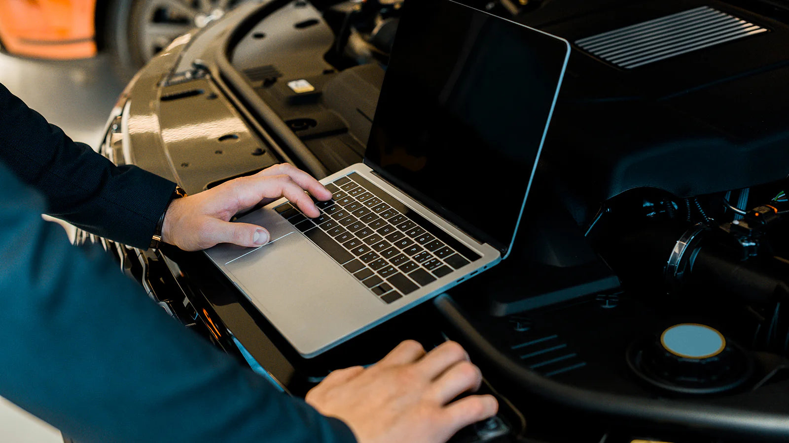 A laptop connected to a car's onboard computer for ECU tuning and engine optimization.