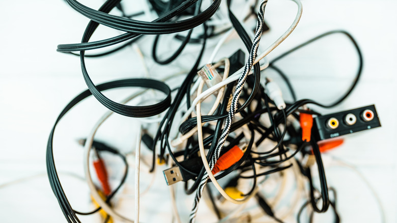 A chaotic tangle of various white and black electronic charging cables.