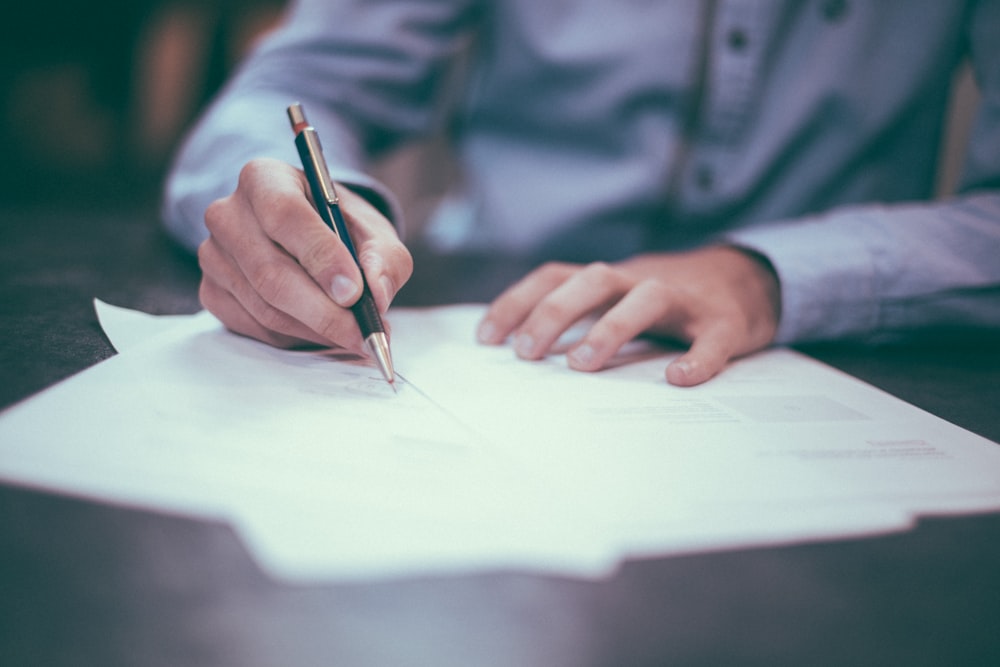 A legal professional reviewing a stack of compliance documents and digital reports.