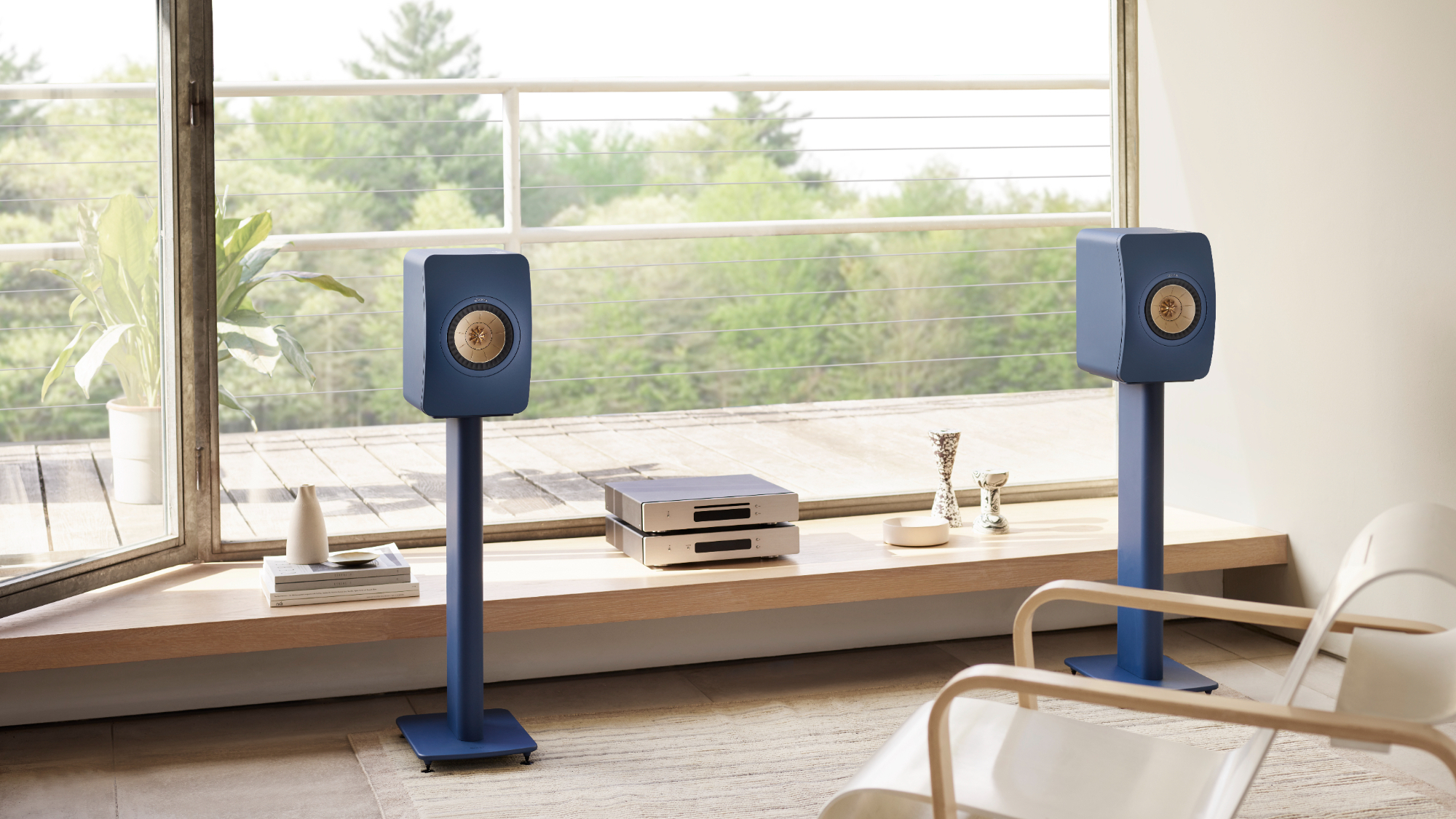 A pair of royal blue KEF LS50 Meta speakers styled in a modern living room setting.