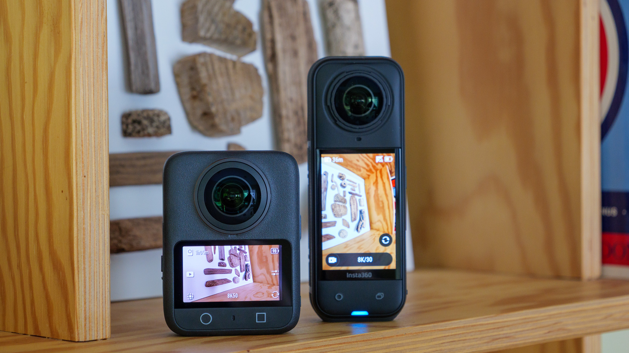 The DJI Osmo 360 and Insta360 X5 sitting together on a wooden shelf.