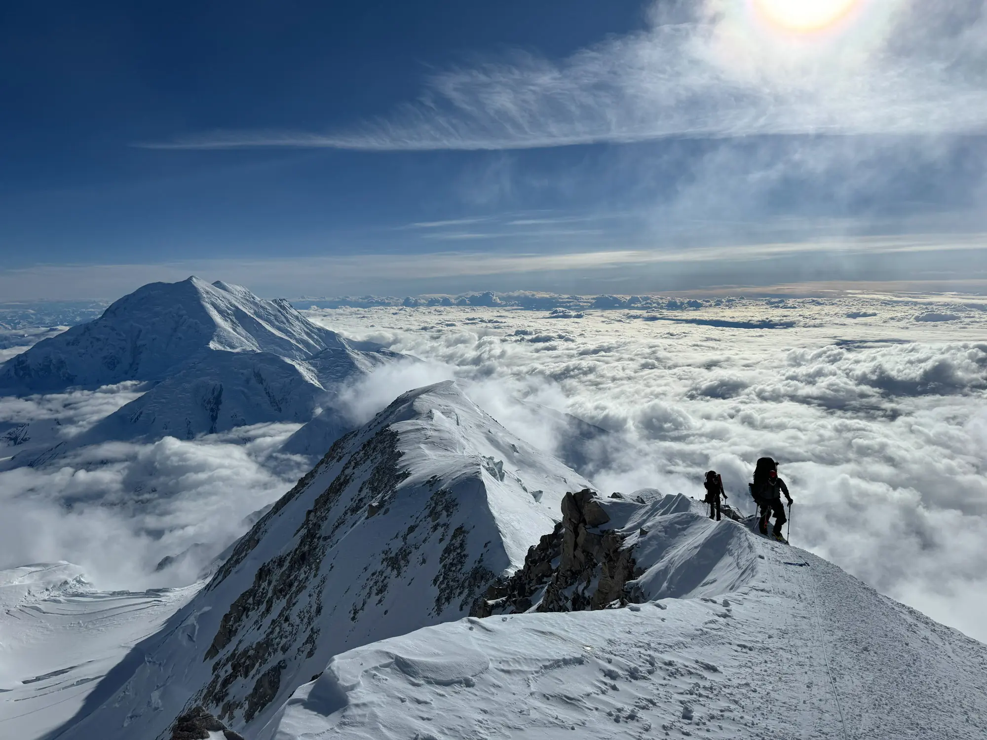 Mountain climbers navigating a narrow, snowy ridge on Denali.