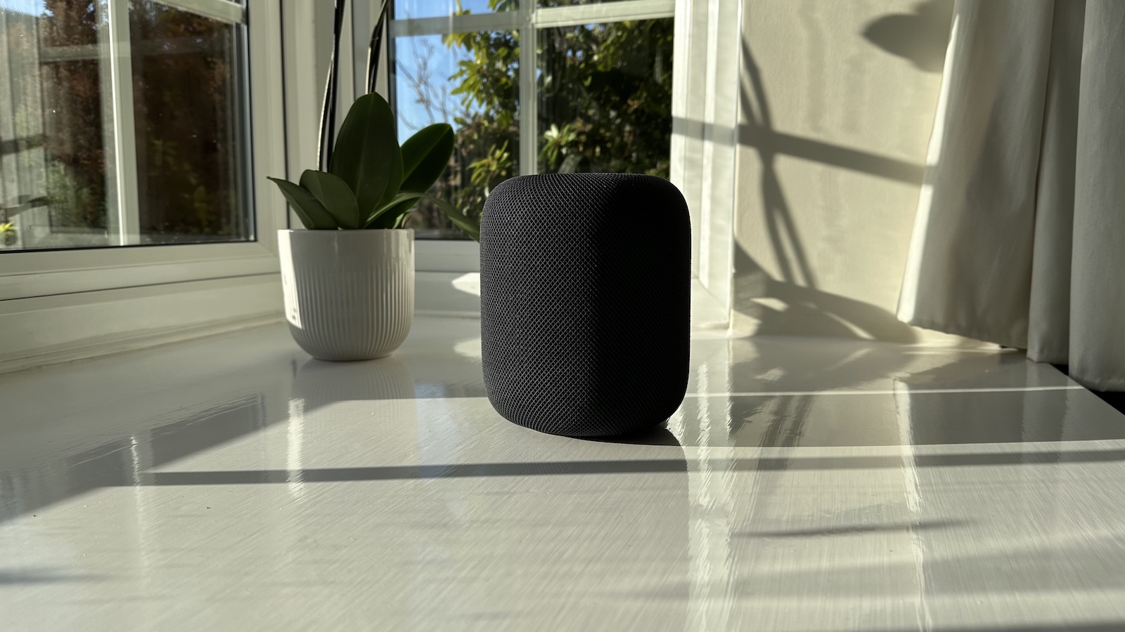 Apple HomePod 2nd Generation speaker sitting on a bright window sill.