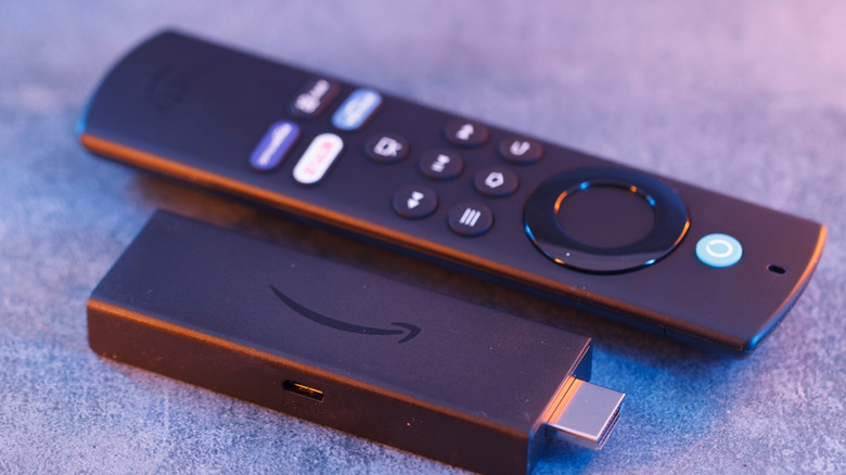 Close up of an Amazon Fire TV Stick and its corresponding Alexa voice remote on a flat surface.