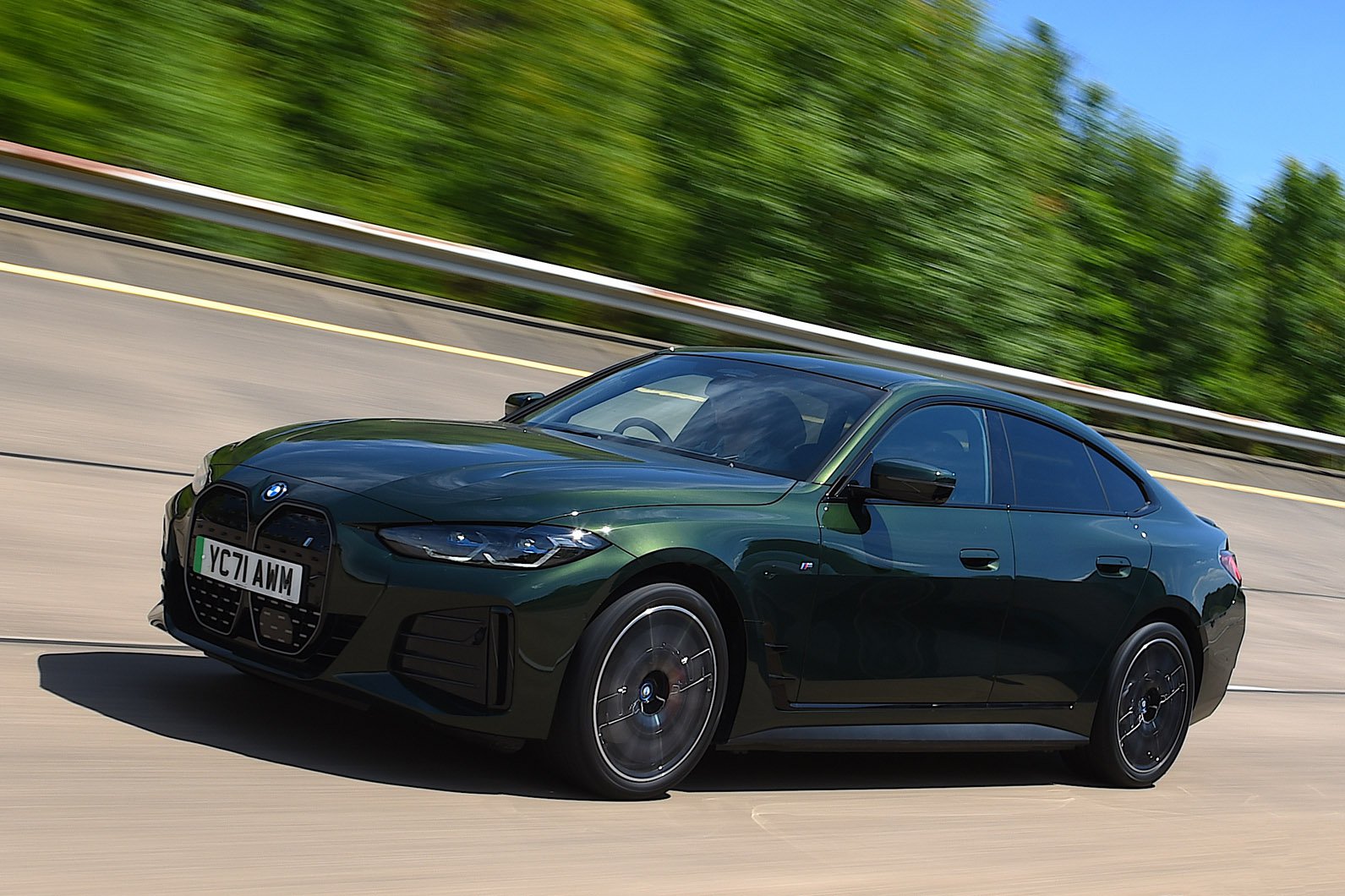 Front quarter tracking shot of a blue BMW i4 driving.